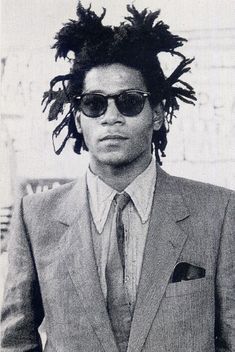 a man with dreadlocks wearing a suit and sunglasses