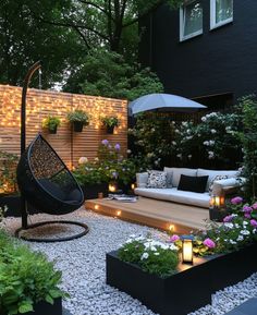 an outdoor living area with plants and lights on the ground, including a swing chair