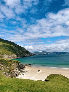 an empty beach with green grass and blue water