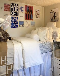 a bedroom with white bedding and lots of pictures on the wall, including a teddy bear