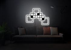 a couch sitting in front of a black wall with glowing squares on it's back