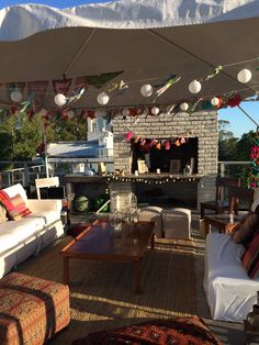 an outdoor living area with couches, tables and lamps hanging from the rafters