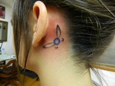 a woman's behind the ear has a small flower tattoo on her left side