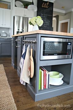 a kitchen island with a microwave and bookshelf on it in front of a chalkboard wall