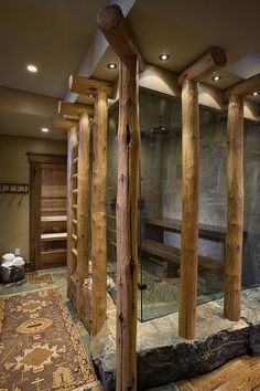 a bathroom with wooden fixtures and a glass shower stall in the center, along with a rug on the floor