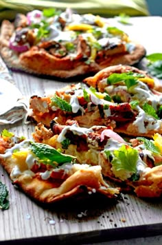 several small pizzas with various toppings are on a cutting board, ready to be eaten