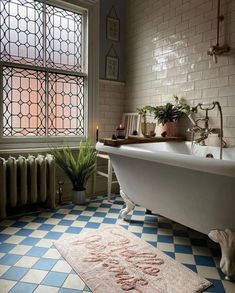 a bath tub sitting next to a window in a bathroom with blue and white tiles