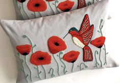 two embroidered pillows with red flowers and a humming bird on the front one is white