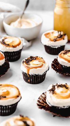 cupcakes with frosting and caramel toppings on a white tablecloth