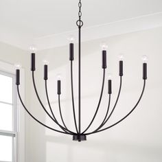 a black chandelier hanging from the ceiling in a room with white walls and windows