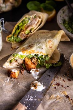 a burrito cut in half on top of a cutting board next to a knife