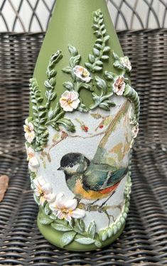 a green vase sitting on top of a wicker table next to leaves and flowers