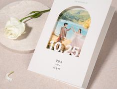 a wedding photo book with a white rose on the table next to it and an image of a couple holding hands