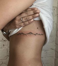 a woman's stomach with a mountain tattoo on it