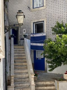 an alleyway with stairs leading up to a blue door and white wallpapered building