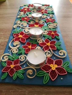 some candles are sitting on top of a blue mat with poinsettias and leaves