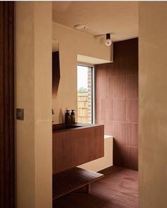 a bathroom with a wooden bench next to a window