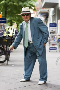 an older man in a suit and tie is walking down the street with his cane