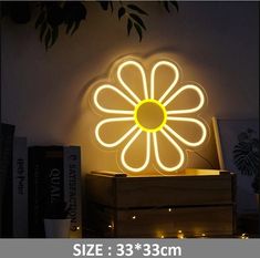 a flower shaped neon sign sitting on top of a wooden box in front of a wall