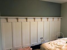 a bed sitting in a bedroom next to a wall with white paneling on it