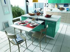 a modern kitchen with green cabinets and white counter tops is pictured in this image, the dining table has four chairs around it