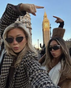 two beautiful young women standing next to each other in front of a building with a clock tower