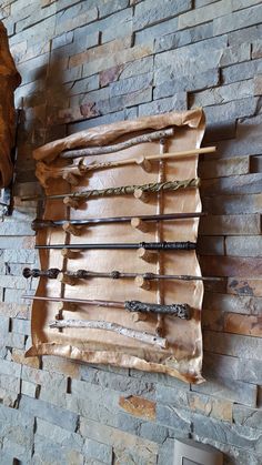 an old brick wall with several arrows hanging on it's side and another piece of wood in the background