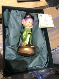 a small figurine in a box with a tag on it's side