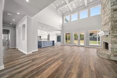 an empty living room with wood flooring and large windows in the ceiling, along with stone fireplace mantels