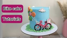 a blue cake with balloons and a pink bike on it