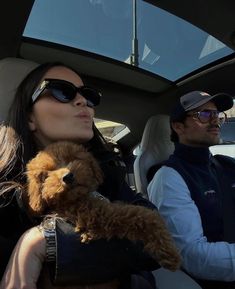 a man and woman sitting in the back seat of a car with a dog on their lap