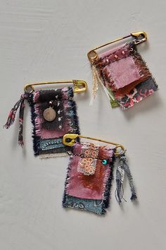 three pieces of fabric hanging from hooks on a white surface, with buttons and tassels attached to them