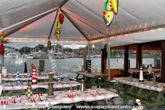 tables and chairs are set up under a tent at the water's edge for an outdoor party