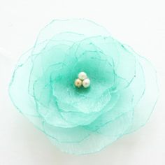 a close up of a flower on a white surface with two pearls in the center