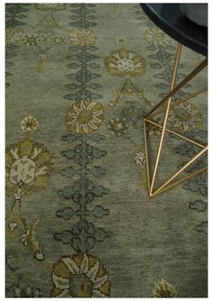 a green rug with gold and blue designs on the floor next to a black chair