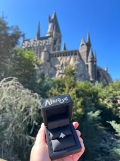 a person holding up a ring in front of a castle with the word always written on it