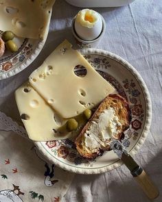 two plates with different types of cheese and bread on them, one has olives