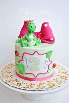 a birthday cake decorated with two green and pink dinosaurs