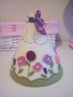 a small white hat with flowers and a butterfly on the top, sitting on a table