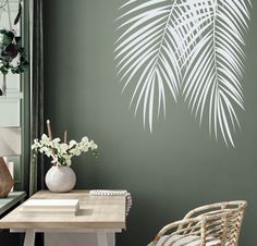 a room with green walls and a white palm leaf wall decal on the wall