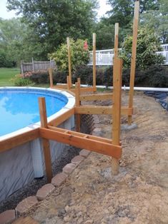 an above ground swimming pool surrounded by rocks and wood posts with a fence around it