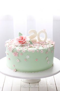 a green cake with pink flowers and the number twenty on top is sitting on a white plate