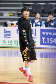 a young man standing on top of a basketball court