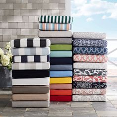 a stack of towels sitting on top of a tiled floor next to a vase filled with flowers