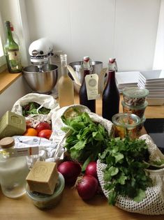 the kitchen counter is cluttered with vegetables and condiments, including eggs, tomatoes, onions, parsley, cheese, milk, butter, and other ingredients