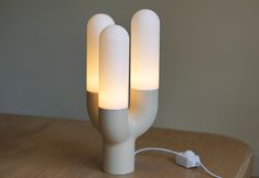 a white lamp sitting on top of a wooden table next to a plugged light