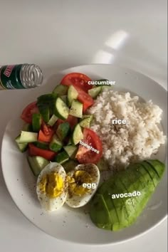 a white plate topped with rice, cucumber, avocado and tomatoes