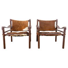 two chairs made out of wood and cow hides are shown side - by - side