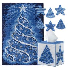 a cross stitch kit with blue christmas trees and stars on it, next to a tissue dispenser