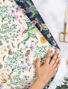 a woman's hand on the edge of a floral wallpaper